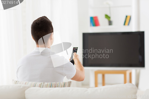 Image of man watching tv and changing channels at home
