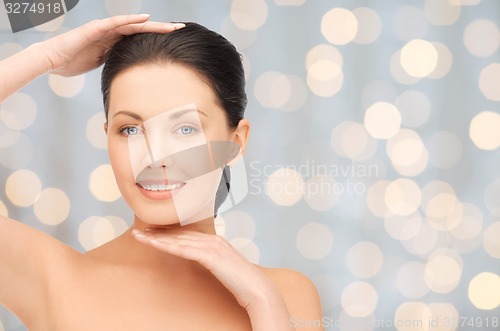 Image of beautiful young woman touching her face and chin