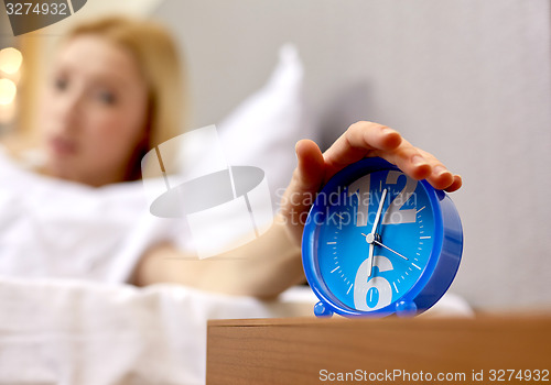 Image of close up of hand on alarm clock in bedroom