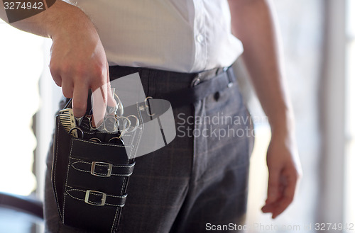 Image of close up of male stylist with tool case at salon