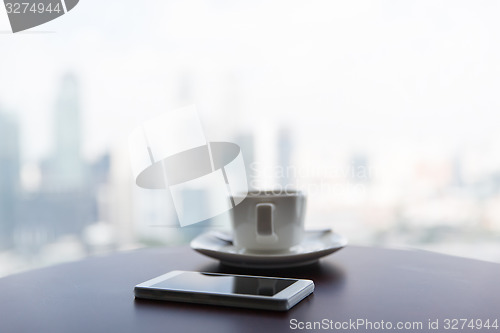 Image of close up of smartphone and coffee cup on table