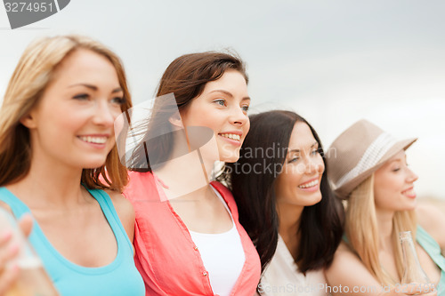 Image of smiling girls with drinks on the beach