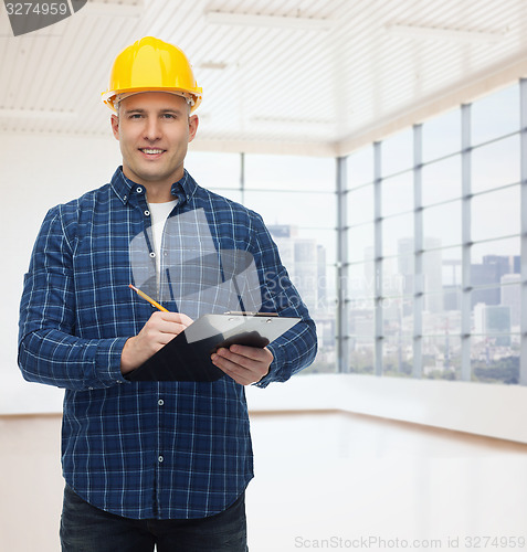 Image of smiling male builder in helmet with clipboard