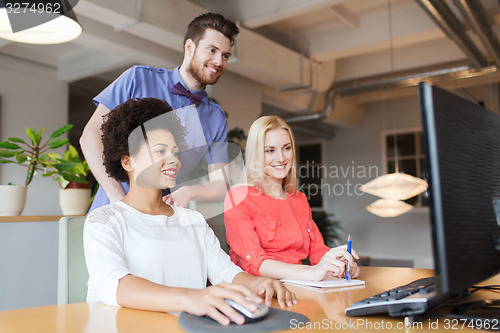 Image of happy creative team with computer in office