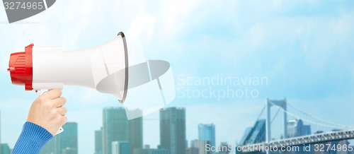 Image of woman hand holding megaphone over city background