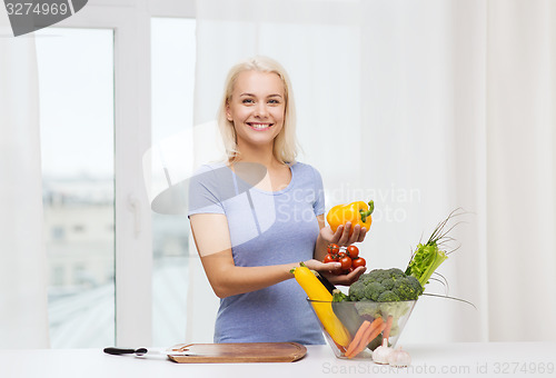 Image of smiling young woman cooking vegetables at home