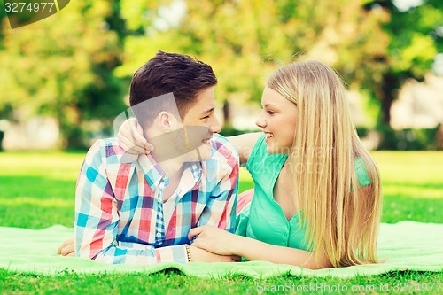 Image of smiling couple lying on blanket in park