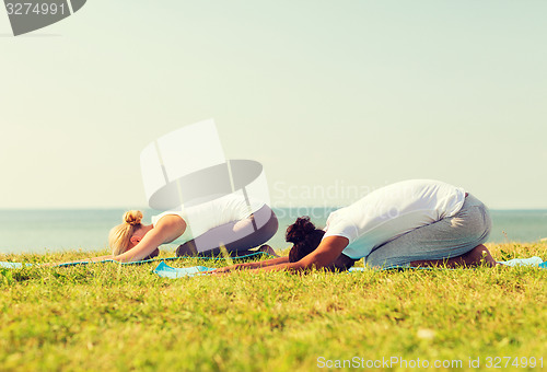 Image of couple making yoga exercises outdoors