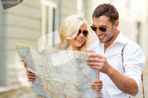 Image of smiling couple in sunglasses with map in the city