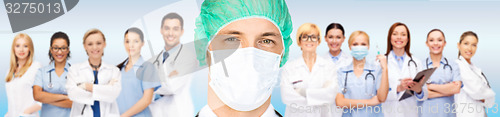 Image of surgeon in medical cap and mask over team