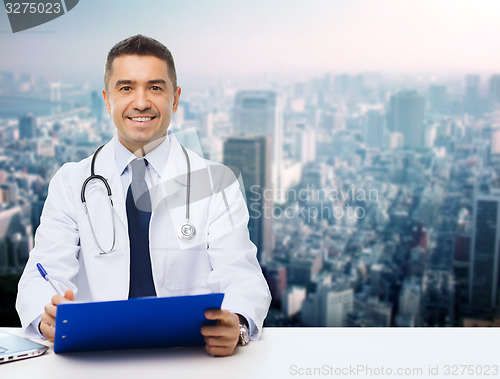 Image of happy doctor with clipboard over city background