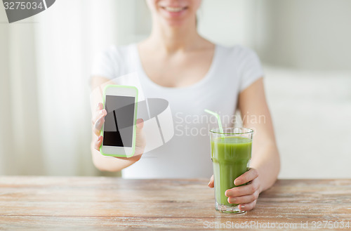 Image of close up of woman with smartphone and green juice