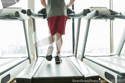 Image of close up of male legs running on treadmill in gym