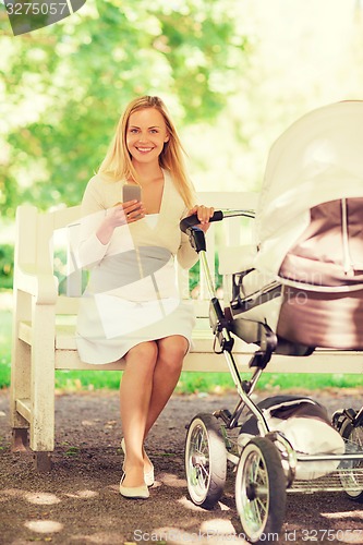 Image of happy mother with smartphone and stroller in park