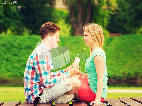 Image of smiling couple with smartphone and earphones