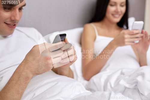 Image of close up of smiling couple in bed with smartphones