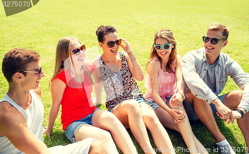 Image of group of smiling friends outdoors sitting in park
