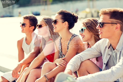 Image of group of smiling friends sitting on city square