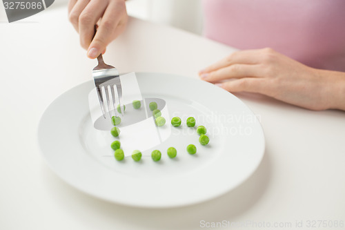 Image of close up of woman with fork eating peas