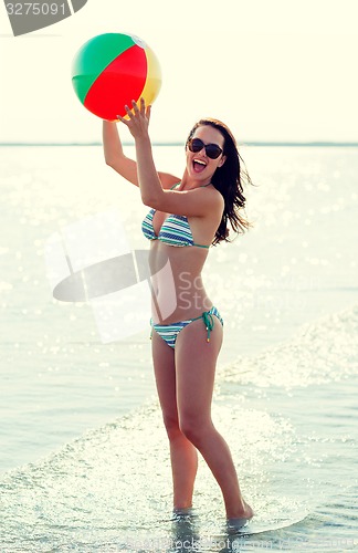 Image of smiling teenage girl sunglasses with ball on beach