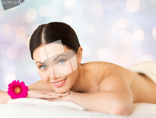 Image of happy beautiful woman lying on massage desk at spa