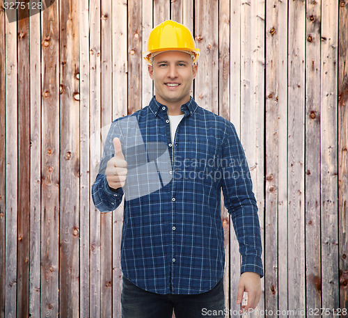 Image of smiling male builder in helmet showing thumbs up