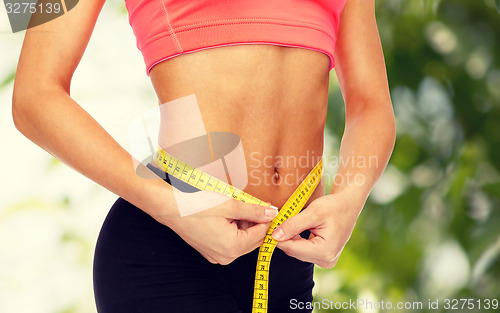 Image of close up of female hands measuring waist