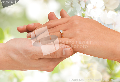 Image of close up of man and woman hands with wedding ring