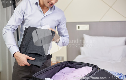 Image of businessman packing clothes into travel bag