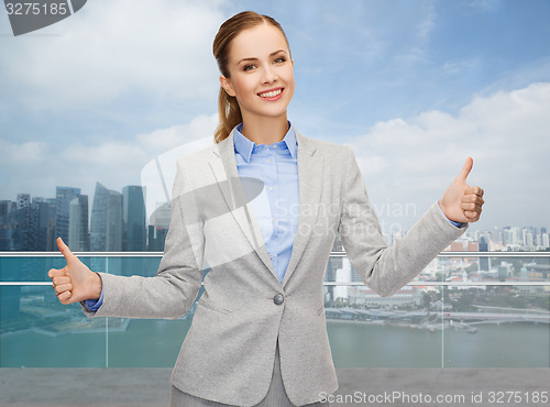 Image of smiling businesswoman showing thumbs up