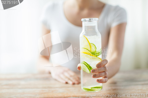 Image of close up of woman with fruit water in glass bottle