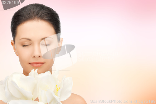 Image of beautiful woman smelling flowers with closed eyes