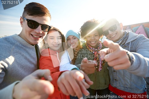 Image of happy teenage friends pointing fingers on street