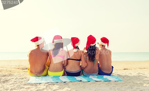 Image of group of friends in santa helper hats on beach