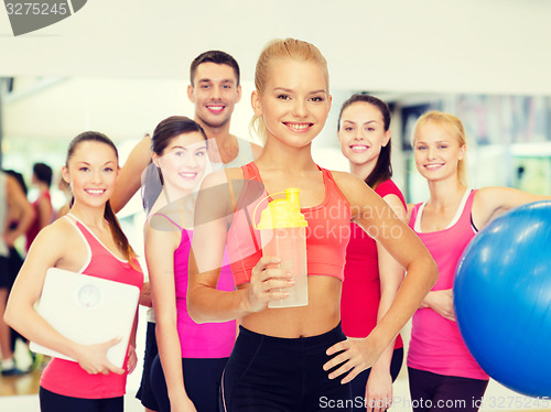 Image of smiling sporty woman with protein shake bottle