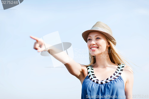 Image of girl in hat showing direction on the beach