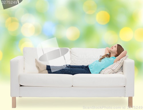 Image of smiling little girl lying on sofa and dreaming