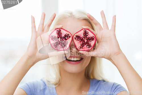 Image of happy woman covering eyes with pomegranate