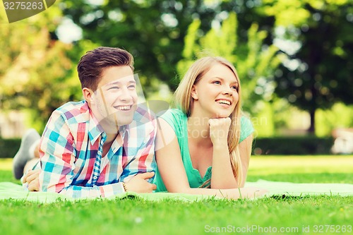 Image of smiling couple lying on blanket in park