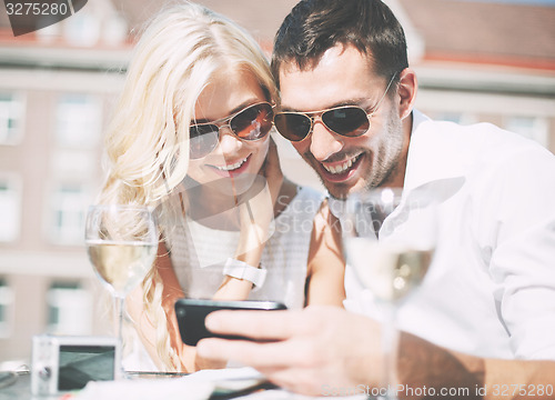 Image of couple looking at smartphone in cafe