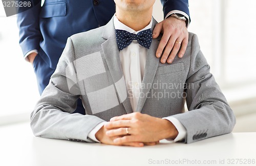 Image of close up of male gay couple with wedding rings on