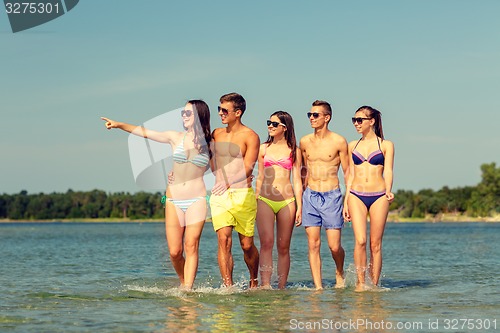 Image of smiling friends in sunglasses on summer beach