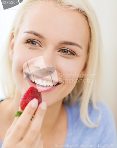 Image of happy woman eating strawberry at home