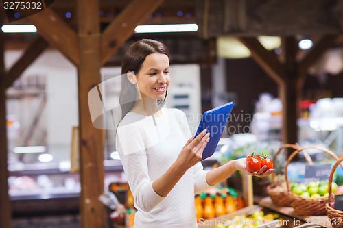 Image of happy woman with basket and tablet pc in market