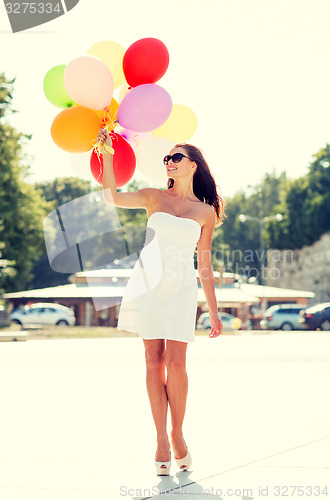 Image of smiling young woman in sunglasses with balloons