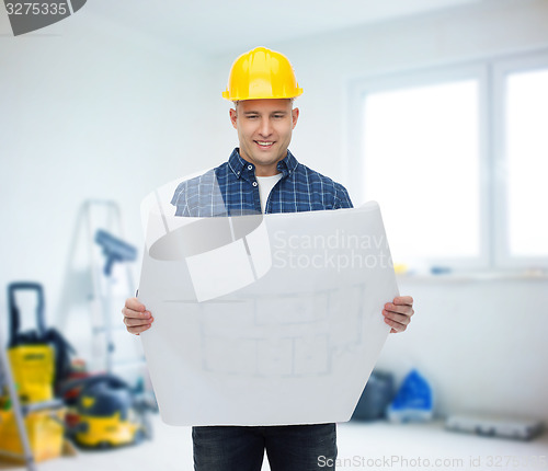 Image of smiling male builder in helmet with blueprint