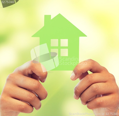 Image of woman hands holding green house