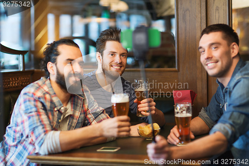 Image of friends taking selfie and drinking beer at bar