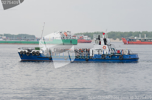 Image of small boat on background of standing in the roads tankers