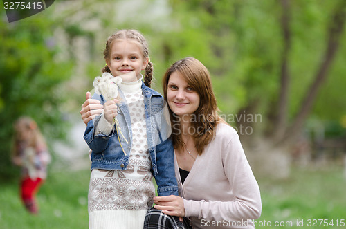 Image of young woman embraces her daughter with dandelions